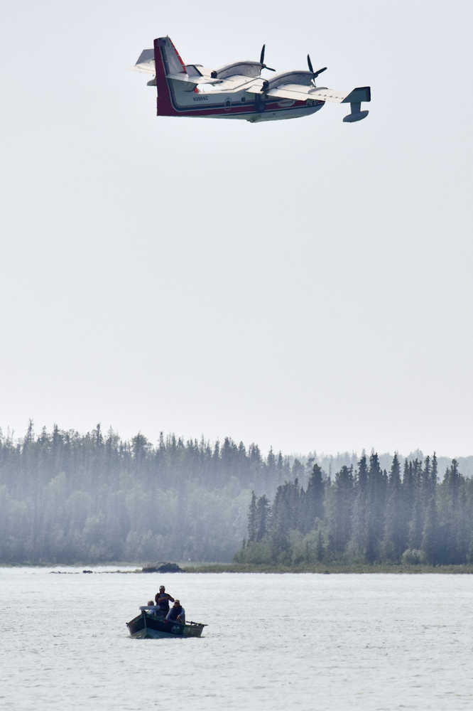 Photo by Rashah McChesney/Peninsula Clarion  A group of fishermen watch as a water bomber takes water from Skilak Lake to fight the Card Street wildfire on Tuesday June 16, 2015 near Sterling, Alaska. The group, a guide from the Silent Run Guide Service and two fishermen from Connecticut and Massachusets said they'd fished for just over an hour as ash fell from the fire onto the Kenai River. Authorities have evacuated the Upper and Lower Skilak Lake campgrounds and closed part of Skilak Loop Road - though the boat ramps remain open.
