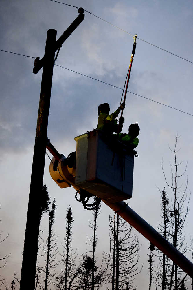 Photo by Rashah McChesney/Peninsula Clarion  HEA linemen work on the power lines in the early morning hours as spot fires burn close by near the Kenai Keys subdivision where the Card Street fire has burned thousands of acres and several structures.