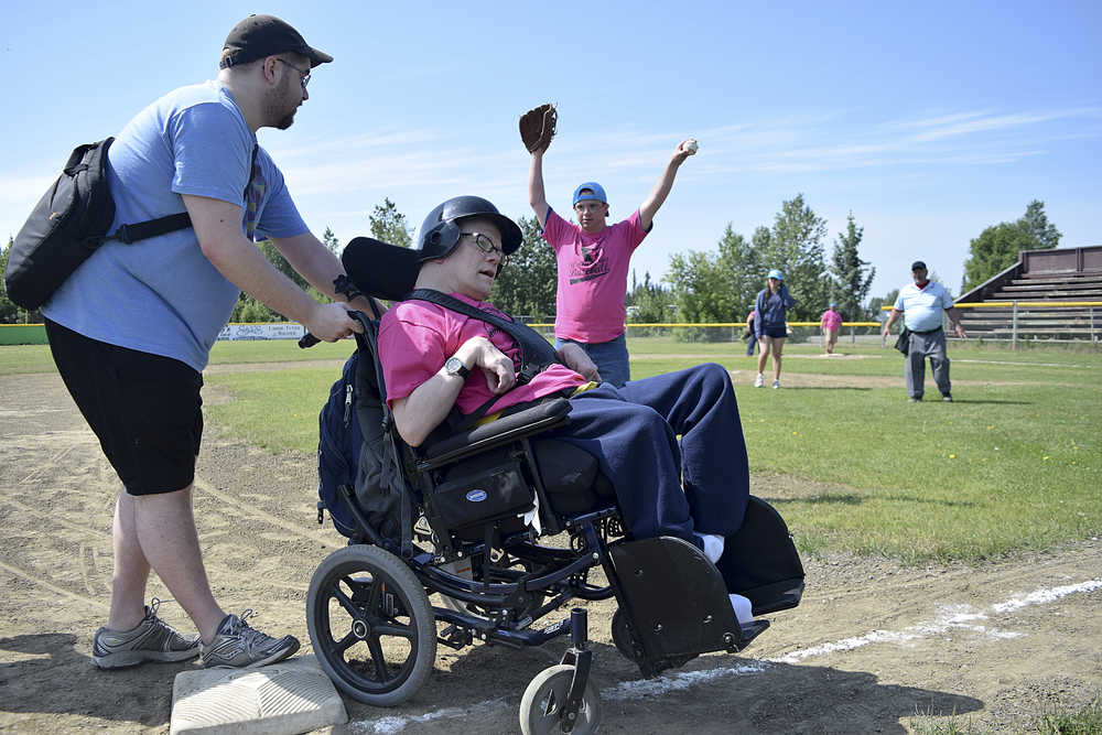 Photo by Rashah McChensey/Peninsula Clarion Isaac Cryer helps Chuck Davis, both of Soldotna, round third base during the annual World Series of Baseball event for community members with developmental disabilities on Friday June 19, 2015 in Soldotna, Alaska.