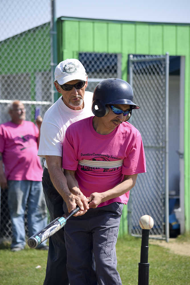 Photo by Rashah McChesney/Peninsula Clarion  A caretaker helps Jacob Dotomain, of Seward, bat during the annual World Series of Baseball event for community members with special needs on Friday June 19, 2015 in Soldotna, Alaska.