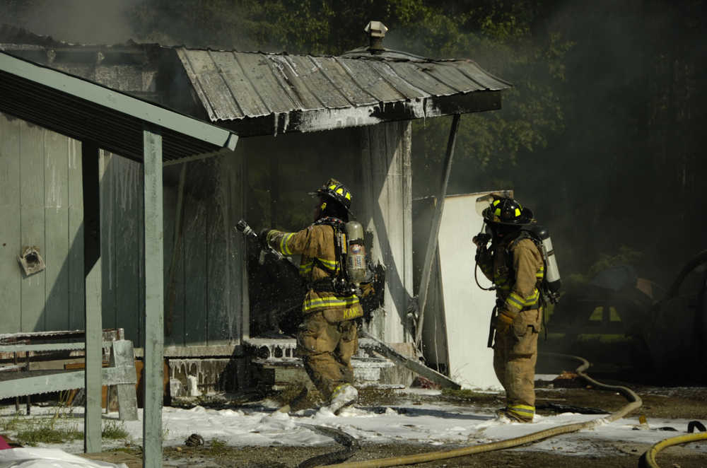 Nikiski Fire Department personnel work on a fire on Arness Road in nikiski Monday.