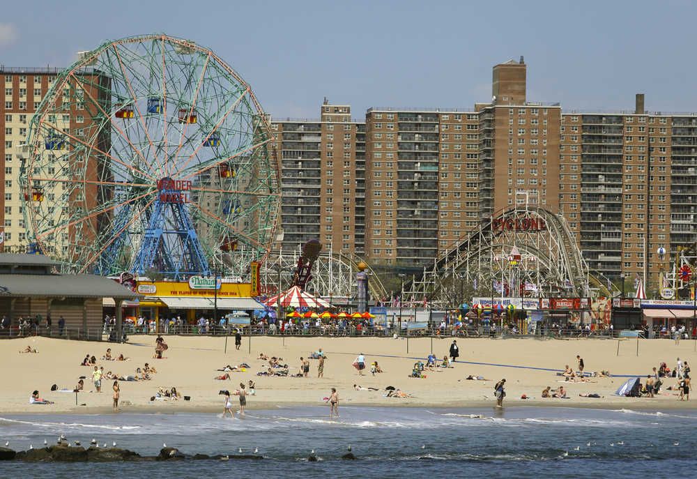 FILE - In this May 20, 2014 file photo, pedestrians walk along the boardwalk past the Wonder Wheel Tuesday in the Coney Island section of the Brooklyn borough of New York. Summer fun at Coney Island just got some new attractions in addition to the beach and amusement park rides. Now visitors can enjoy colorful murals and artisanal food vendors selling everything from truffle fries to hibiscus ice pops. Coney Art Walls launched this week a block from the boardwalk and right behind Nathan's Famous, the hot-dog emporium. Some of the same street artists whose work can be seen in Miami's popular Wynwood neighborhood were brought in to decorate outdoor walls for the food-and-art experience.  (AP Photo/Frank Franklin II, File)