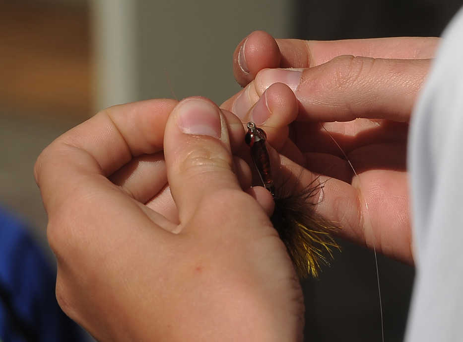 In this photo taken on June 16, 2015, a young angler participating in the Next Cast Flyfishers camp ties on a small streamer while preparing to fish for rainbow trout in Shevlin Park pond, in Bend, Ore. (Ryan Brennecke /The Bulletin via AP)