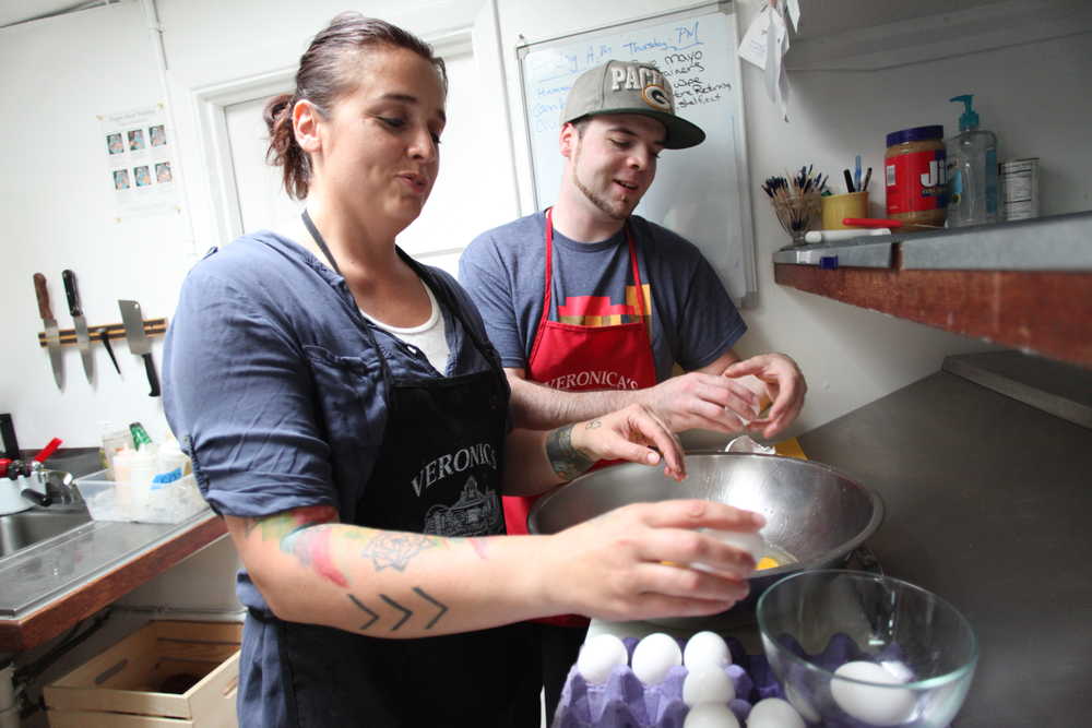 Photo by Kelly Sullivan/ Peninsula Clarion Cooks Nita Jackson and Tyler Hall crack eggs for the quiche Hall will be making Thursday, July 2, 2015, at Veronica's Cafe in Kenai, Alaska.