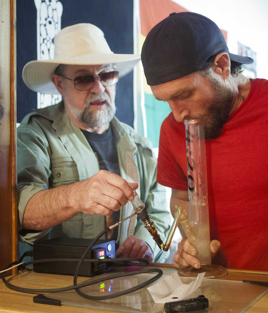 Kirk Daman, of Homer, (left) helps Logan Jensen, of Homer, (right) sample a cannabis product on Saturday at the Green Rush Events Clubhouse in Kenai. Photo by Megan Pacer/Peninsula Clarion