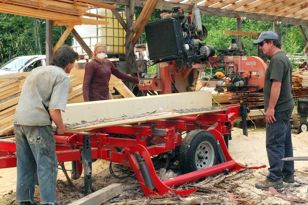 In this May 29, 2015 photo, From left to right, Sterling Chew, Kelsey Kennedy and Gordon Chew work at a lumber mill for a project in Denali National Park and Preserve in Corner Bay, Alaska. The Chews own Tenakee Logging Company. They were awarded their first contract by the U.S. Forest Service in 2007. Now, the Chews have two lumber mills and have gradually accumulated the heavy equipment that helps in the lumber trade. (Mary Catharine Martin/ Capital City Weekly via AP)