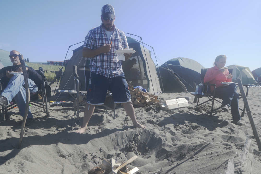 Ben Boettger/Peninsula Clarion Dipnetters John Collins (left), Jeremy Coulson (center,) and Chelsee Largo (right) eat a brunch of bacon and eggs at their encampment on Kenai's north beach on Sunday, July 19.