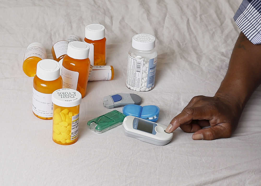 In this Monday, July 13, 2015 photo Earl Charles Williams Sr., 59, sits next to some of the medication he must take for his diabetes in his Chicago home. Williams was uninsured for about a year before a county-run clinic helped him sign up for care under the Affordable Care Act.  More than a dozen states that opted to expand Medicaid under the Affordable Care Act have seen enrollments surge way beyond projections, raising concerns that the added costs will strain their budgets when federal aid is scaled back starting in two years.   (AP Photo/Christian K. Lee)