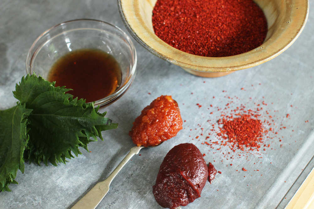 This June 22, 2015 photo shows, from top right clockwise, Korean chili flakes, gochujang, ssamjang, perilla leaves, and fish sauce in Concord, N.H. The rise of Korean food in the U.S. is driven by its pantry ingredients, not traditional restaurants. (AP Photo/Matthew Mead)