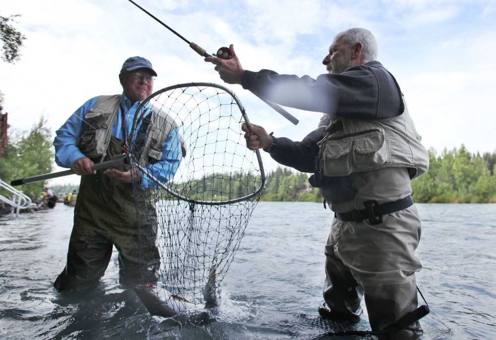 Ben Boettger/Peninsula Clarion Sam Gotter (left) nets a sockeye pulled in by Pat Homer (right) on the Kenai River in Soldotna on Tuesday, July 21.