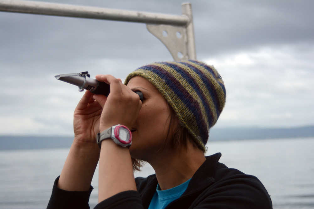 Becca Miathias looks through a refractometer to measure salinity in an ocean water sample taken.