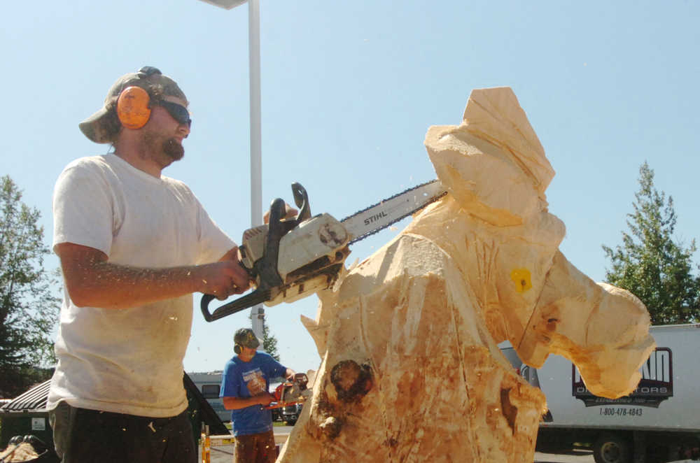 Megan Pacer/Peninsula Clarion Jeff Eshom, a chainsaw sculptor at Soldotna's Town of Living Trees, works on a carving of a moose during the Sawfest Chainsaw Carving Competition in Centennial Park on Friday, July 25.