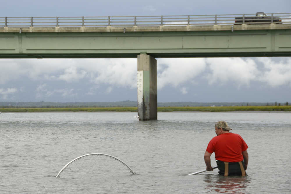 Ben Boettger/Peninsula Clarion Dipnetter Travis Richards wets his net in the Kenai River under Warren Ames Bridge on Tuesday, July 28.