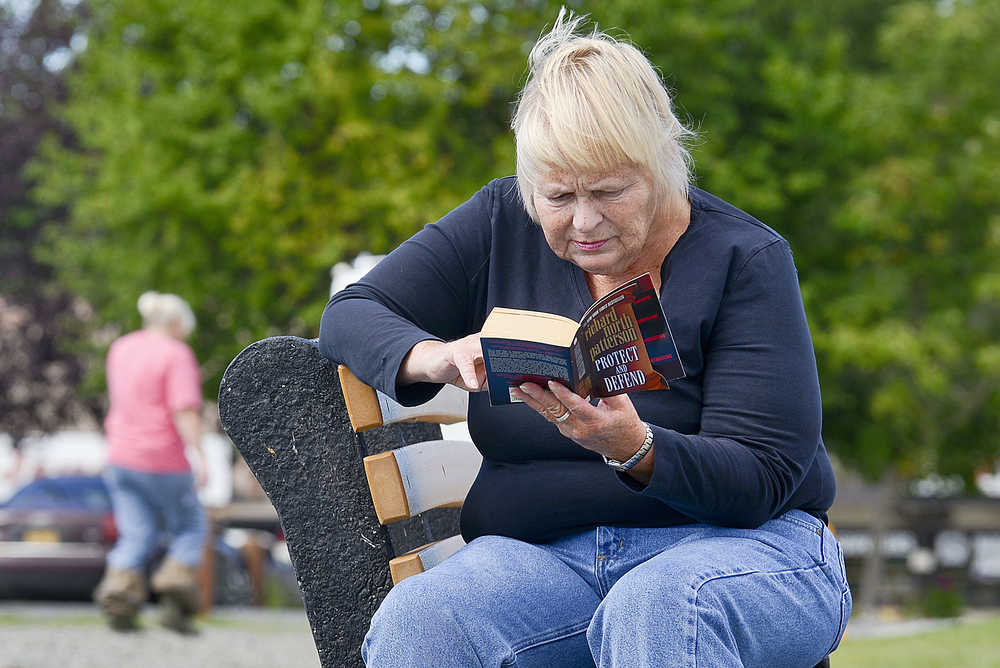 Photo by Rashah McChesney/Peninsula Clarion  Griselda Mustard, of Soldotna, reads Richard North Patterson's "Protect and Defend" on a sunny day Thursday July 30, 2015 at Soldotna Creek Park.