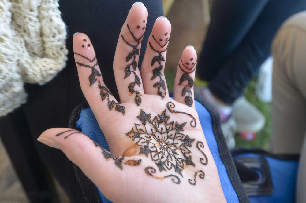Photo by Megan Pacer/Peninsula Clarion A festival-goer admires her hand after receiving a henna tatoo on Friday July 31, 2015 in Ninilchik, Alaska. Several vendors offered henna, in addition to glitter tatoos and massages.