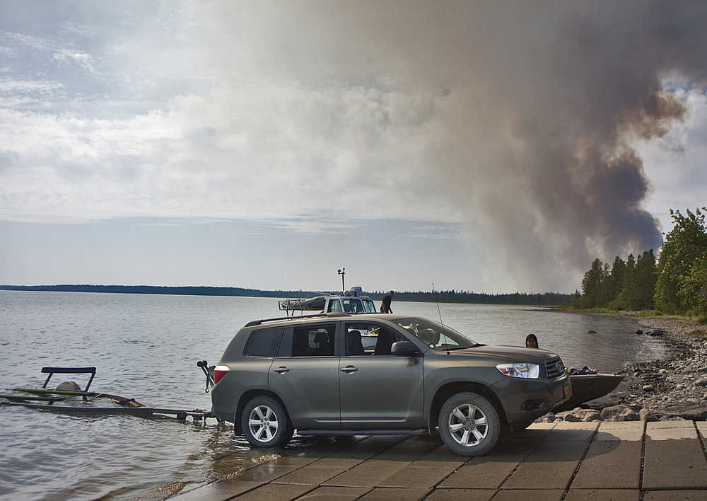 Photo by Rashah McChesney/Peninsula Clarion Boats come and go from the Upper Skilak Campground boat launch with smoke from the Card Street wildfire in the background on June 16. Fire crews involved in repairing damage to the landscape caused by firefighting efforts are using caution in the area due to lingering smoke and hot spots, as well as danger from falling trees.