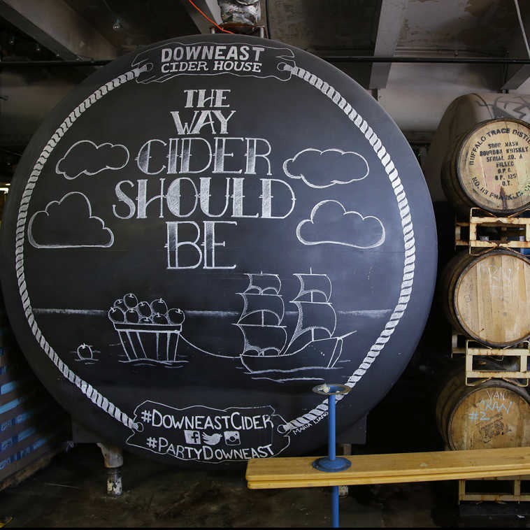 A storage tank,  wooden whiskey barrels and cider cans are displayed at the Downeast Cider House home office Friday, July 24, 2015, in Boston. The company expects to produce 17,000 barrels of cider this year, more than doubling overall production compared to last year. (AP Photo/Stephan Savoia)