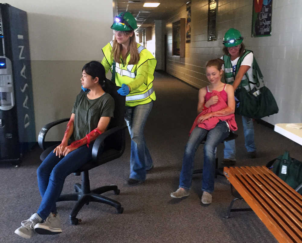 Photo by Megan Pacer/Peninsula Clarion Leah Vik (left) and Daughn Carpenter (right) wheel volunteers posing as victims out of an earthquake simulation held Saturday Aug. 8, 2015, at Soldotna Prep School in Soldotna, Alaska. This summer's volunteers for Community Emergency Response Team training were made up mostly of Girl Scouts and Boy Scouts.