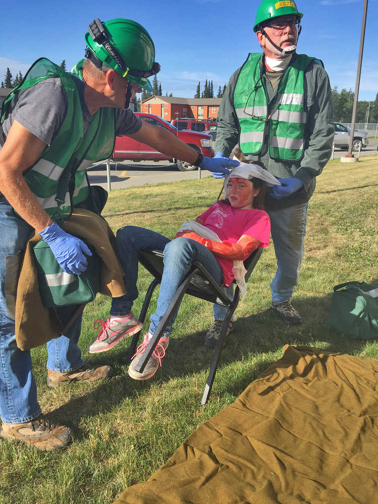 Photo by Megan Pacer/Peninsula Clarion Community Emergency Response Team course members Charles See (left) and John Eller (right) prepare to treat 11-year-old Kellee Martin for fake injuries during a simulated earthquake exercise held Saturday Aug. 8, 2015 at Soldotna Prep School in Soldotna, Alaska.