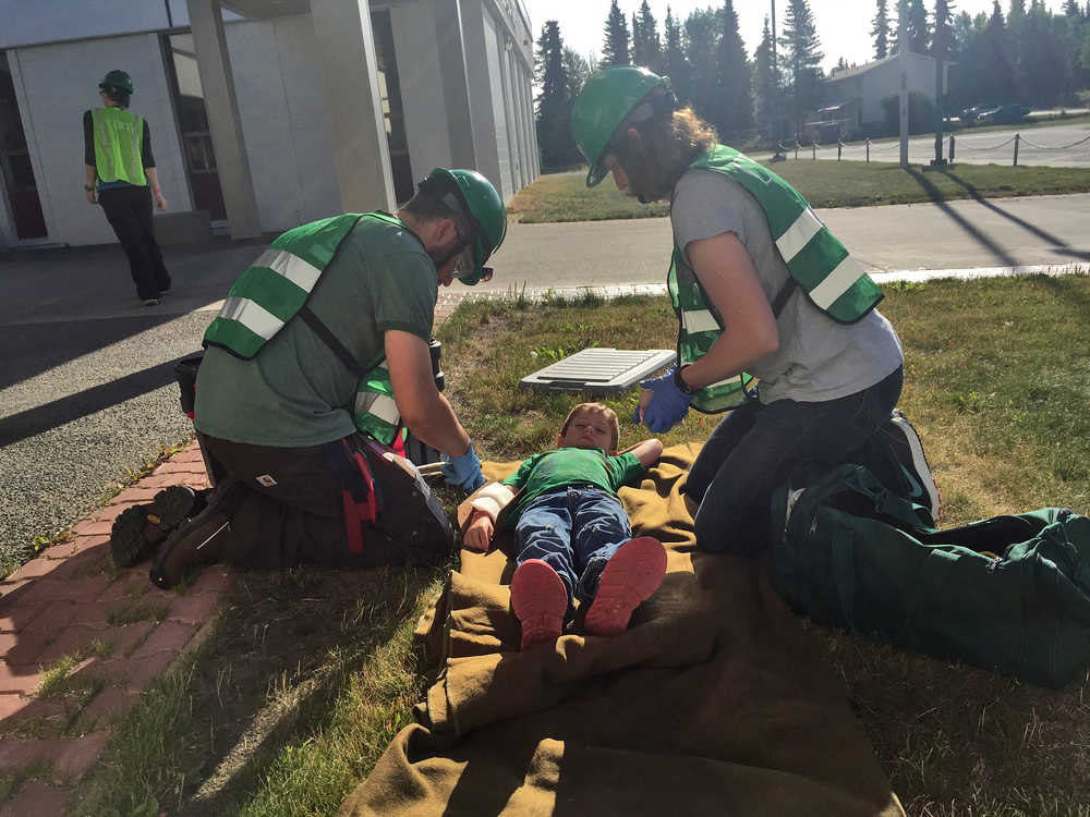 Photo by Megan Pacer/Peninsula Clarion Community Emergency Response Team course members Jeremiah Millette (left) and Melissa Daugherty (right) treat 5-year-old Lyman Winger for fake injuries during a simulated earthquake exercise held Saturday Aug. 8, 2015, at Soldotna Prep School in Soldotna, Alaska.