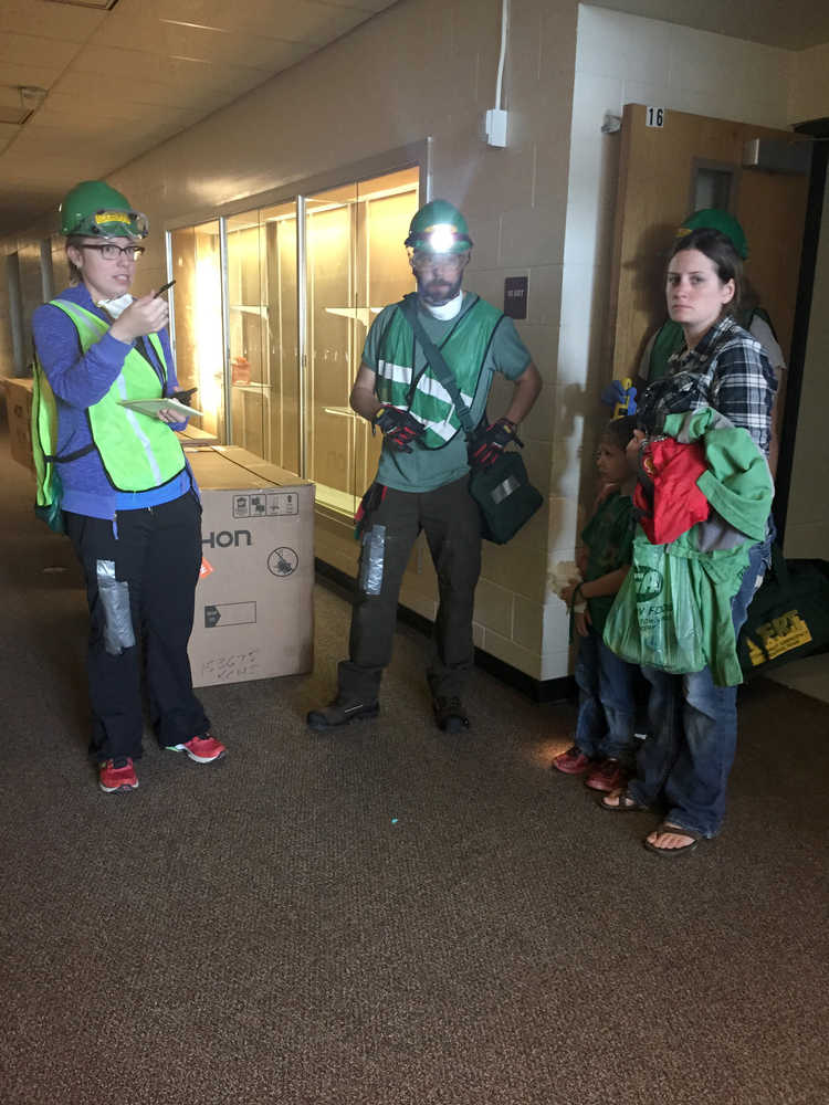 Photo by Megan Pacer/Peninsula Clarion Community Emergency Response Team course members K.J. Hillgren (left), Jeremiah Millette (center) and volunteer victims strategize during a simulated earthquake exercise held Saturday Aug. 8, 2015 at Soldotna Prep School in Soldotna, Alaska.