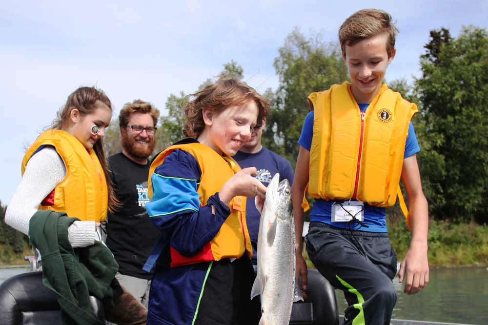 Ben Boettger/Peninsula Clarion From left to right: Olivia Loehr, guide Drew Anderson,  (with a silver salmon he caught) and Scott Loehr exit a boat during the Take Our Kids Fishing event at Soldotna's Centenial Park on Thursday, August 13.