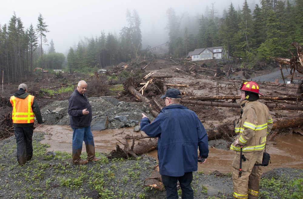 From left, city engineer Dan Tadic, Fire Chief Dave Miller, Search and Rescue Capt. Lance Ewers, and firefighter Rob Janik look at the damage caused by a landslide on Kramer Drive Tuesday, Aug. 18, 2015 in SItka, Alaska.  Four residents of a neighborhood in Alaska were missing Tuesday after heavy rain caused several landslides, emergency responders said. (James Poulson/The Daily Sitka Sentinel via AP) MANDATORY CREDIT
