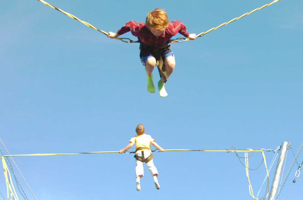 Ben Boettger/Peninsula Clarion  Brothers Grayden (top) and Golden Musgrave bounce on the bungee trampoline at the Ninilchik Fairgrounds during the Kenai Peninsula Fair on Friday, August 21.