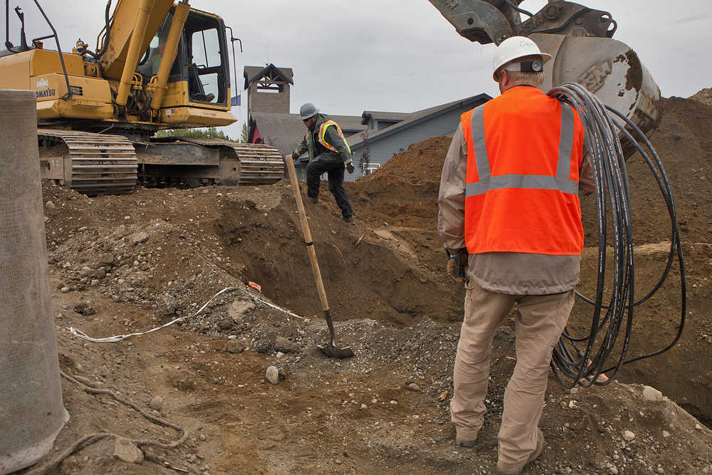 Photo by Rashah McChesney/Peninsula Clarion  (left) Tim Digan and Travis Wetzel, ACS employees, bury the AKORN fiber optic cable as North Star Paving & Construction employees work to remove a hill near Nikiski Fire Station No. 2 on Wednesday August 25, 2015 in Nikiski, Alaska.