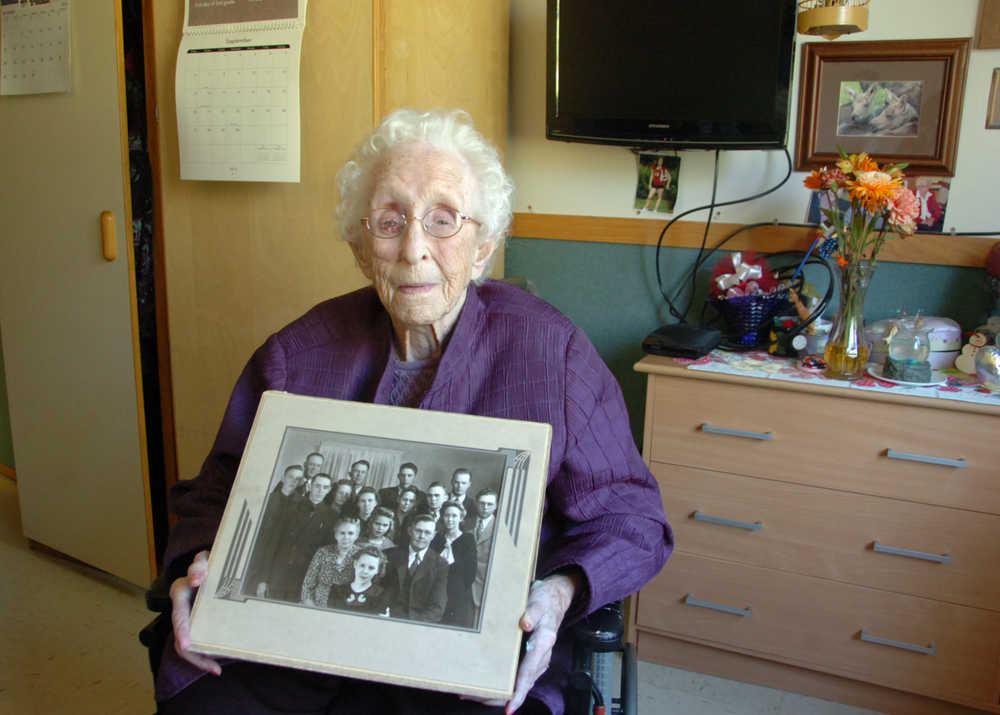 Photo by Megan Pacer/Peninsula Clarion Fern Elam, who turned 105 on Friday, holds a picture of herself with her 13 siblings while relaxing in her room on Tuesday, Sept. 1 2015, at Heritage Place in Soldotna, Alaska.