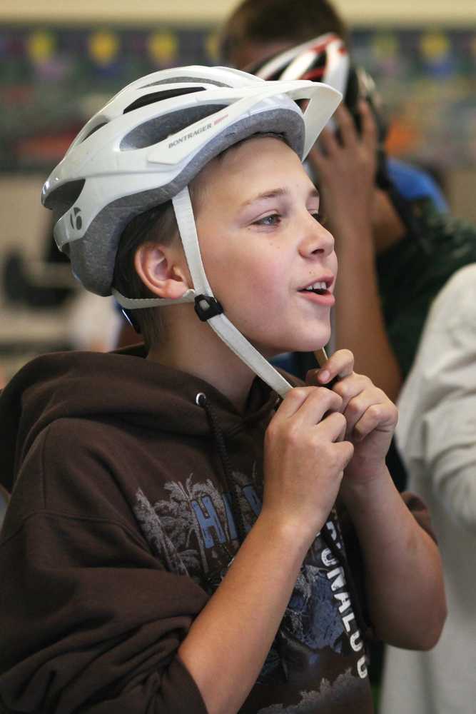 Photo by Kelly Sullivan/ Peninsula Clarion XXX straps on a helmet Wednesday, Sept. 2, 2015, at Kenai Middle School in Kenai, Alaska.