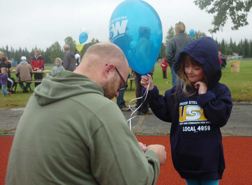 Photo by Megan Pacer/Peninsula Clarion Kenai resident Myles Sansotta (left) helps his 4-year-old daughter, Molli, tie a knot in the string of her balloon on Monday, Sept. 7, 2015 at the annual Labor Day Picnic at Kenai Central High School in Kenai, Alaska.