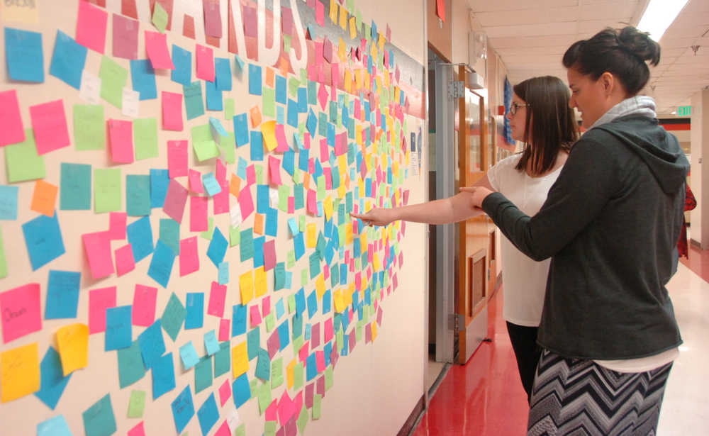 Photo by Megan Pacer/Peninsula Clarion Leslie Fazio (background) and Laura Beeson point out positive messages on the "Wall of Hope" they had high school students create as part of the new statewide Suicide Prevention Week, on Thursday, Sept. 10, 2015 at Kenai Central High School in Kenai, Alaska.