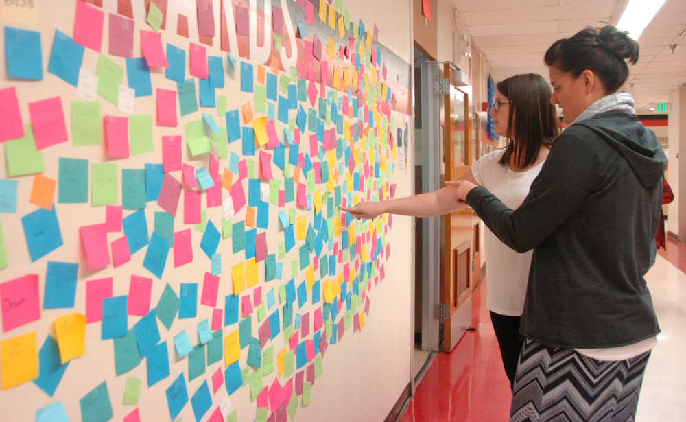 Photo by Megan Pacer/Peninsula Clarion Leslie Fazio (background) and Laura Beeson point out positive messages on the "Wall of Hope" they had high school students create as part of the new statewide Suicide Prevention Week, on Thursday, Sept. 10, 2015 at Kenai Central High School in Kenai, Alaska.