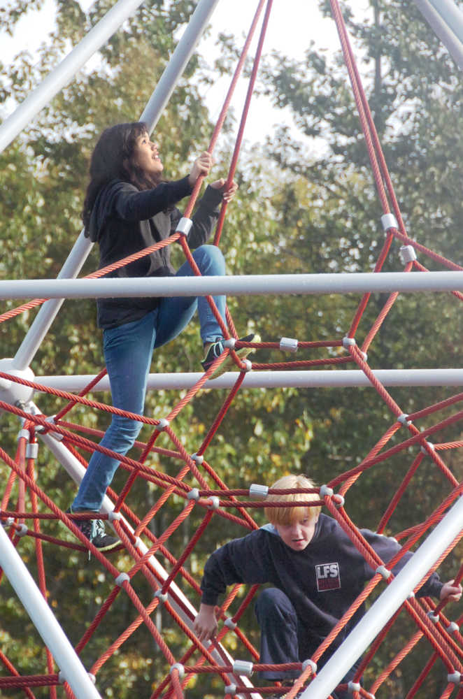 Ben Boettger/Peninsula Clarion Maddy Triana (left) and Cooper Collier climb on the spider-web pyramid in Kenai Municipal Park during the park's dedicaiton on Saturday, September 12 in Kenai.
