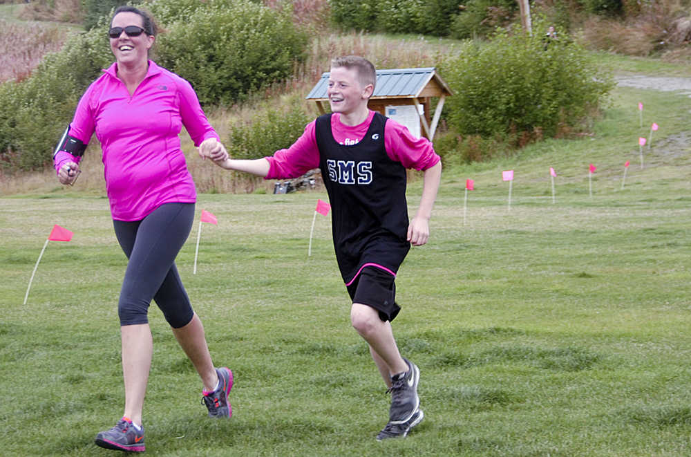 Photo by Megan Pacer/Peninsula Clarion Soldtona resident April Chilton crosses the finish line of the Making Strides Against Breast Cancer Walk/Run with her 13-year-old son, Lance, who looped back to join her after finishing the 5K first, on Sunday, Sept. 13, 2015 at the Tsalteshi Trails in Soldotna, Alaska.
