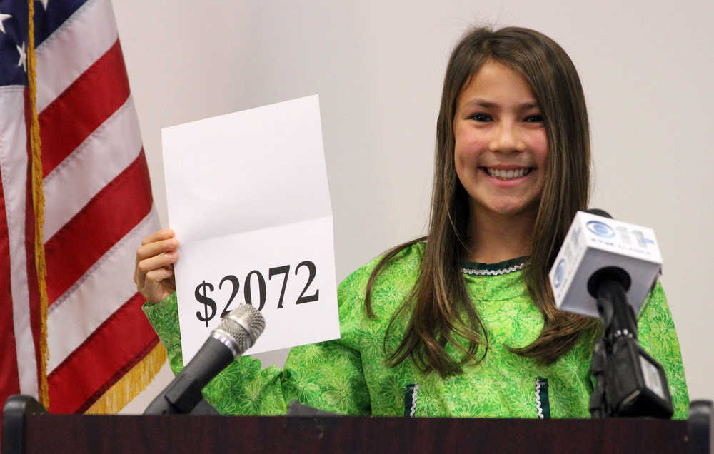 Seventh-grade student Shania Sommer of Palmer, Alaska, announces that nearly every Alaskan will receive $2,072 from this year's oil dividend check during a news conference Monday, Sept. 21, 2015, in Anchorage, Alaska. Sommer was chosen by the office of Gov. Bill Walker to reveal the amount of this year's check. (AP Photo/Mark Thiessen)