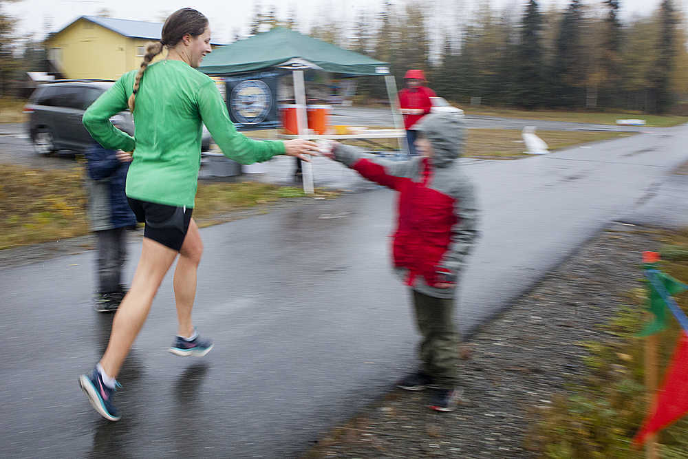 Photo by Rashah McChesney/Peninsula Clarion  Joann Jeplawy takes a cup of water from Samuel Anders at a relay station on the the Kenai River Marathon route along the Kenai Spur Highway on Sunday Sept. 26, 2015 in Kenai, Alaska. Jeplawy finished 18th out of the 97 runners in the half marathon race.