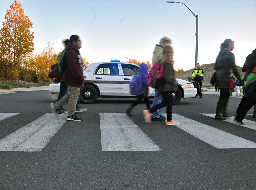 Jane Fellman (right), coordinator of the Safe Kids of the Kenai Peninsula Coalition, hands out string backpacks at the annual walk to school event.