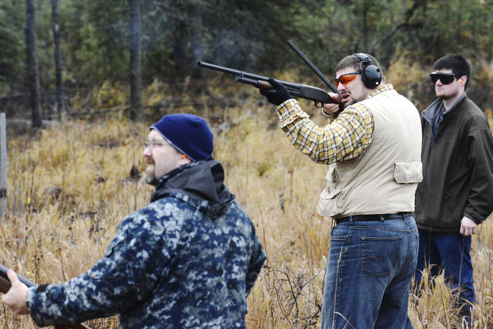 Ben Boettger/Peninsula Clarion Pattrick Morgan (center), flanked by teammates Sterling Rasmuson (left) and Camron Lotti, shoots at a clay pidgeon during the Shoot for a Cure trap-shooting fundraiser on Saturday, Oct. 3 at the Snoeshow Gun Club in Soldotna.