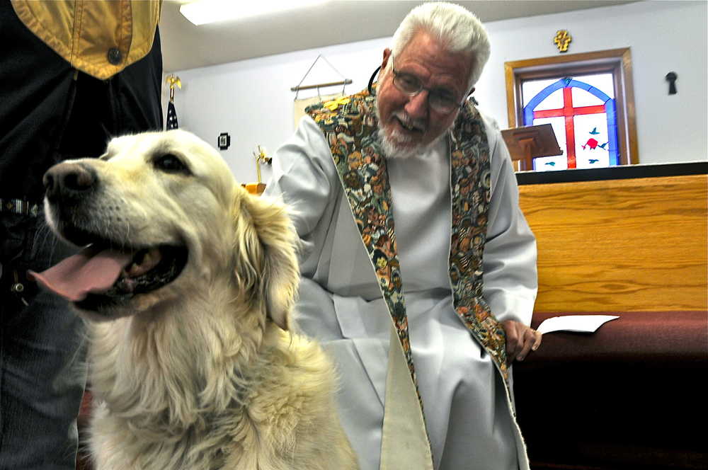 Father Tom Rush of the Our Lady of the Angels Catholic Church in Kenai blesses Max, a white golden retriever, Sunday at the St. Francis by the Sea Church in Kenai. The two churches held a joint Blessing of the Animals event to honor St. Francis, who Rush said honored all life, including animals.
