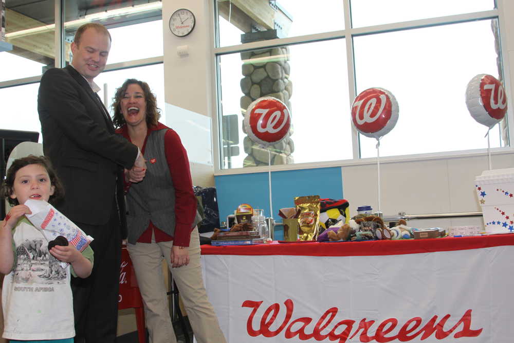 A Walgreens regional manager congratulates Soldotna Store Manager Traci Riddle at the grand opening give-a-way table.