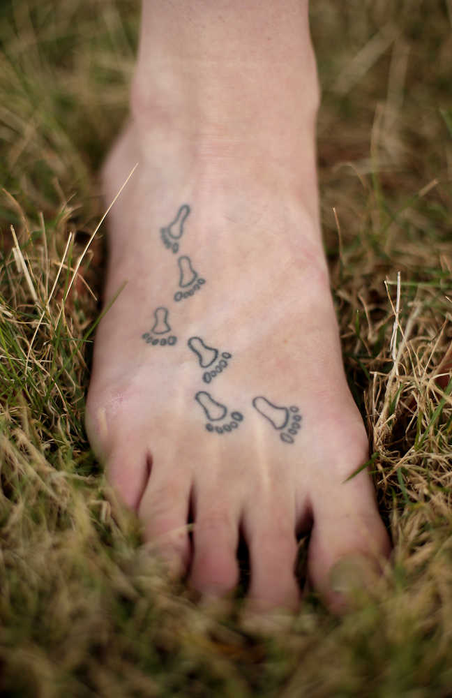 In this photo taken Aug. 28, 2015, Bethany Hughes shows six tattooed footprints on her foot that represent countries she has lived in. Growing up with missionary parents has fostered a wandering spirit in Hughes, who plans to spend five years in an attempt to become the first woman to trek from the southern tip of South America to the northern tip of Alaska all by non-motorized means. (AP Photo/Charlie Riedel)