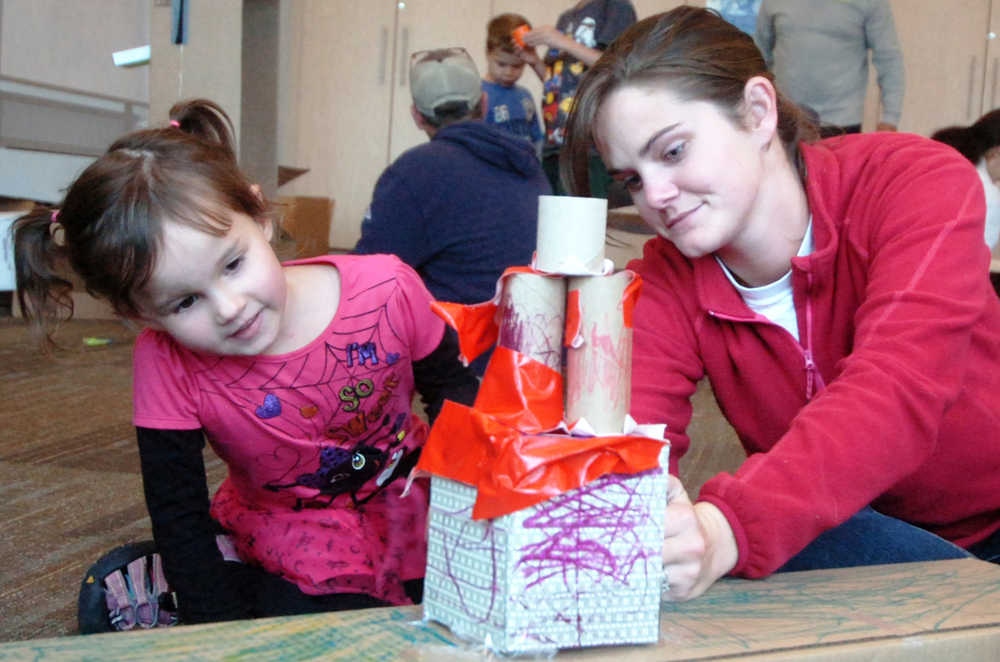 Ben Boettger/Peninsula Clarion Charlotte Wardas (left) and Sarah Gardner construct a house out of cardboard and duct tape during the Cardboard Challenge on Friday, Oct. 9 at the Soldotna Public Library.