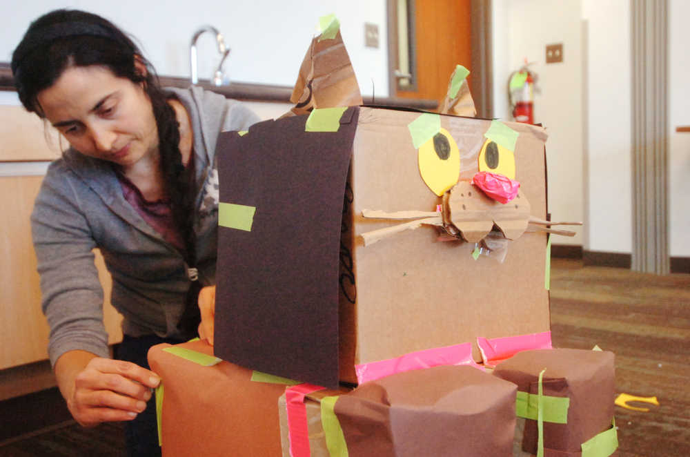 Ben Boettger/Peninsula Clarion Jessica Franklin attachs tape to a cardboard cat she built at the Cardboard Challenge on Friday Oct. 9 at the Soldotna Public Library.