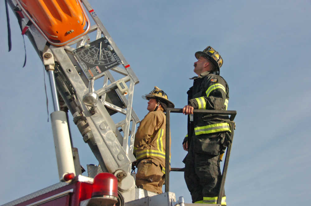 Photo by Megan Pacer/Peninsula Clarion Engineer Shawn Killian, right, helps train Firefighter Spencer McLean, left, how to operate the 75-foot ladder truck owned by Central Emergency Services on Monday, Oct. 19. 2015 in Soldotna, Alaska. Firefighters at CES are training in preparation for an engineering test coming up in November that will test their ability to operate the department's machinery.