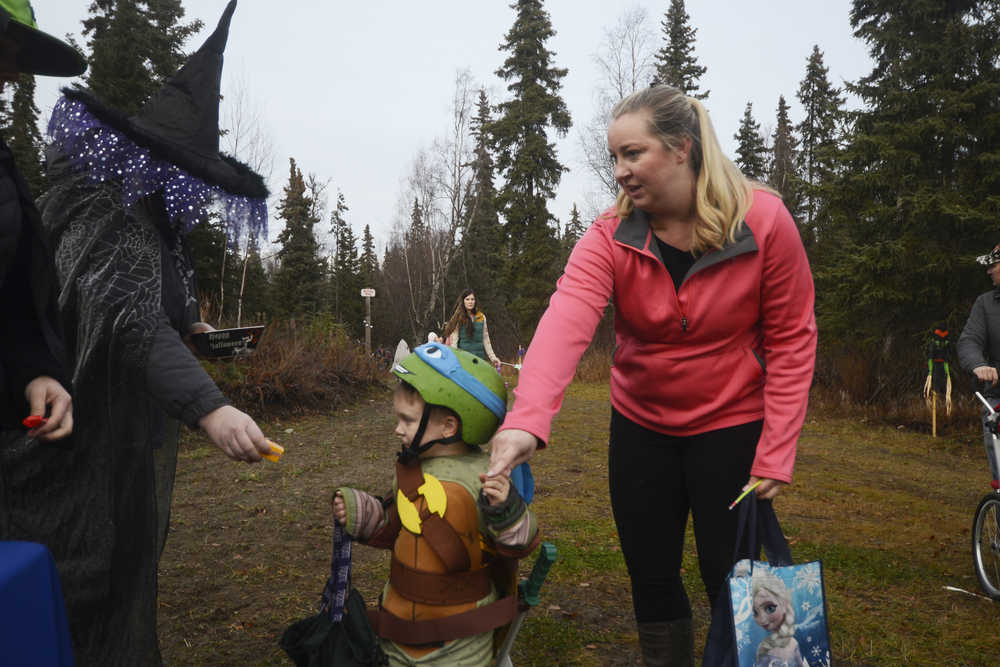 Photo by Megan Pacer/Peninsula Clarion Kenai resident Jill Schaefer guides her 3-year-old son, Cody, through a candy station on Sunday, Oct. 25, 2015 during the annual Spook Night Trick or Treat and Zombie 5K at the Tsalteshi Trails in Soldotna, Alaska.