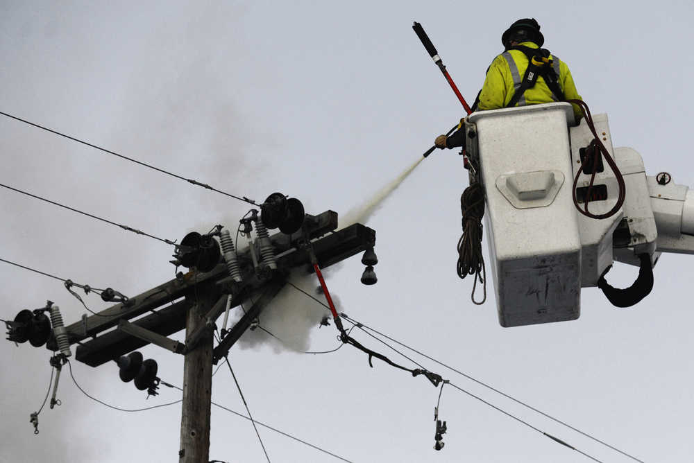 Ben Boettger/Peninsula Clarion Homer Electric Association workers use a fire extinguisher to put out a smoldering crossbeam on an electric pole in Soldotna on Tuesday, Nov. 3 near the intersection of the Kenai Spur highway and Marydale Avenue.