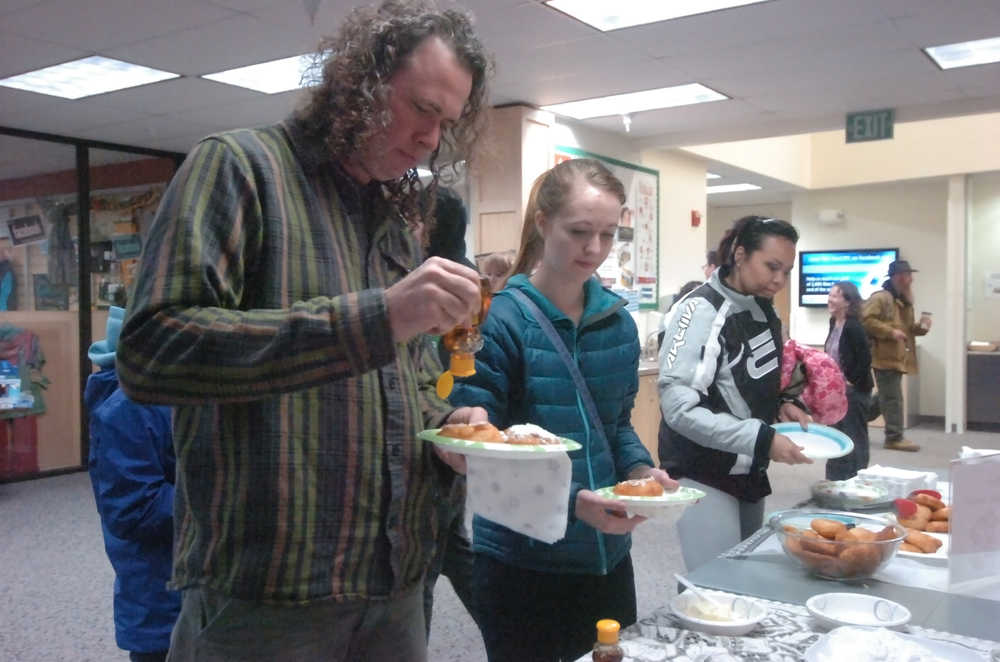 Photo by Megan Pacer/Peninsula Clarion Barnie Weaver, of Kasilof, puts honey on a piece of fry bread during a kick-off event for Alaska Native/Native American Heritage Month on Thursday, Nov. 5, 2015, in the McLane Commons at Kenai Peninsula College.