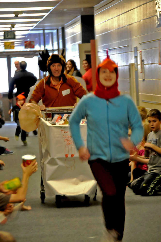 Photo by Elizabeth Earl/The Peninsula Clarion Laney Wattam, a sixth-grader at Redoubt Elementary School, leads borough mayor Mike Navarre down the hallway Friday during the Great Grocery Grab, an annual food drive event hosted by the school.